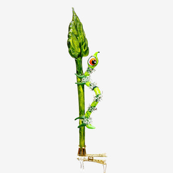 A decorative glass ornament shaped like a green leaf with a caterpillar crawling up it. The caterpillar has a round head with red, orange, and black eyes, white spots, and small green feet.