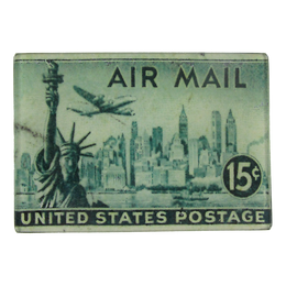 A illustration featuring a United States Air Mail postage stamp with the Statue of Liberty and an illustration of New York City's skyline and a 15 cent denomination. This is on a three and a half inch by five inch glass tray.