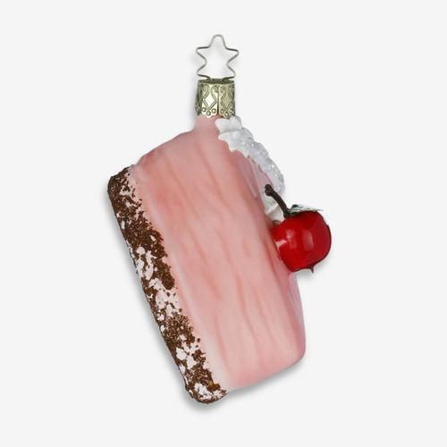 A pink frosted cake Christmas ornament with a brown crumb base, white icing details, a red cherry, and a silver star topper, shown on a light gray background.