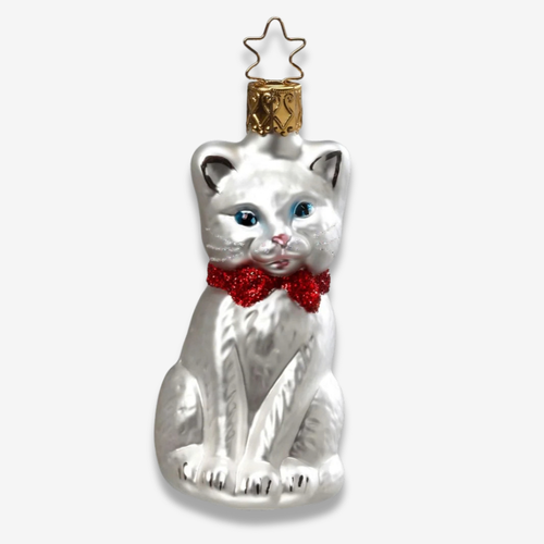 A white glass cat Christmas ornament with blue eyes, a red glitter bow tie, and a gold star topper, shown on a light gray background.