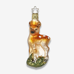 A decorative glass ornament shaped like a fawn, with a warm amber-brown body, white spots, and a glittery green base, hanging from a gold star cap on a light gray background.
