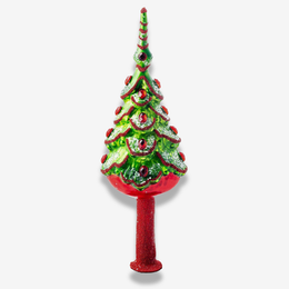 A decorative Christmas tree topper with a glittery green tree body, red scalloped trim, red ornaments, and a red base on a light gray background.