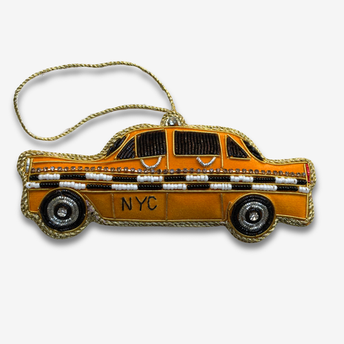 A fabric covered ornament in the shape of a New York City Taxi, with  beads and embroidery on grey background. 