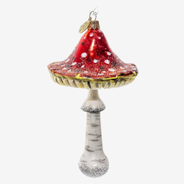 A decorative glass Christmas ornament shaped like a mushroom, featuring a glossy red cap with white speckles, a gold-rimmed edge, and a textured off-white stem with gray speckles, shown against a plain light gray background.