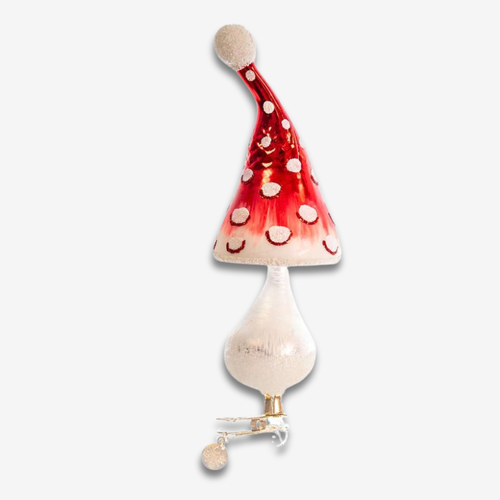 A whimsical mushroom-shaped ornament with a red and white spotted cap, a cream-colored stem, and a small gold-toned metal hanger at the bottom, shown against a plain light gray background.