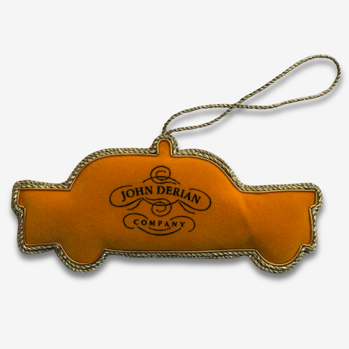 A fabric covered ornament in the shape of a New York City Taxi, with  beads and embroidery on grey background. 