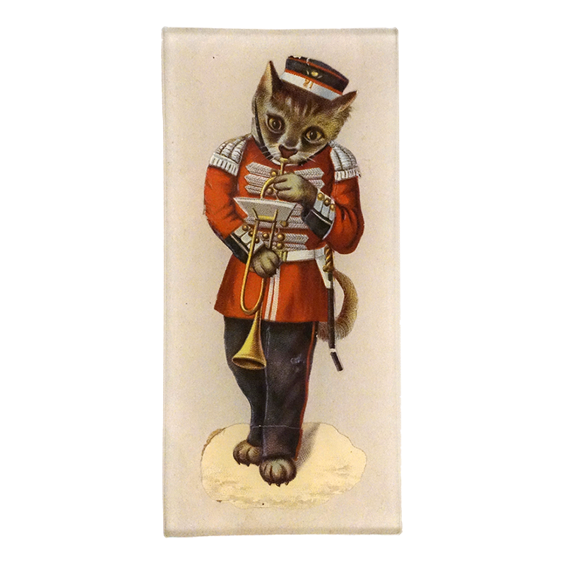An illustration showing a cat dressed in a red military uniform and playing a trumpet on a three and a half inch by seven inch glass tray. 