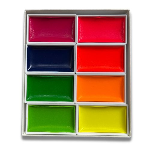 A 12-color watercolor paint palette in a white box, featuring six rectangular pans of paint in pink, red, blue, orange, green, and yellow, arranged in a 2x6 grid on a white background.