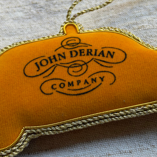 A fabric covered ornament in the shape of a New York City Taxi, with  beads and embroidery on grey background. 