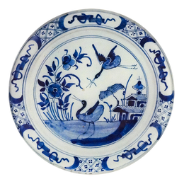 A five inch round glass plate of a blue and white delft design 
