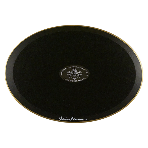 The back of a horizontal oval plate painted black with black felt backing and gold trim. Featuring the John Derian Company sticker and signed by John Derian. 