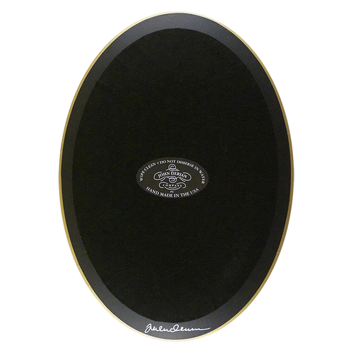 The back of an oval-shaped plate painted black with black felt backing and gold trim. Featuring the John Derian Company sticker and signed by John Derian. 