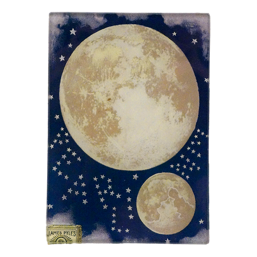 A large moon and a smaller moon surrounded by stars in the night skit on a three and a half inch by five inch glass plate. 