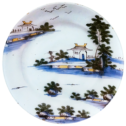 A five inch round blue and white delft plate featuring trees and small houses 