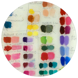 An eleven inch round glass plate with various colorful paint swatches.