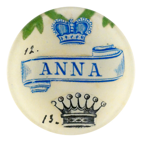 Anna is a four inch round place handmade in our New York City studio featuring the name ANNA in blue font with two crowns 