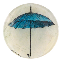 A four inch round homemade decoupage plate of a blue umbrella on a cream backgorund
