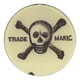 A five inch round glass plate of a skull and crossbones design, and the words 'TRADE MARK' arched across the center.