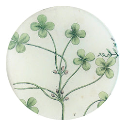 A five inch round glass plate featuring about 6 small four leaf clovers. 