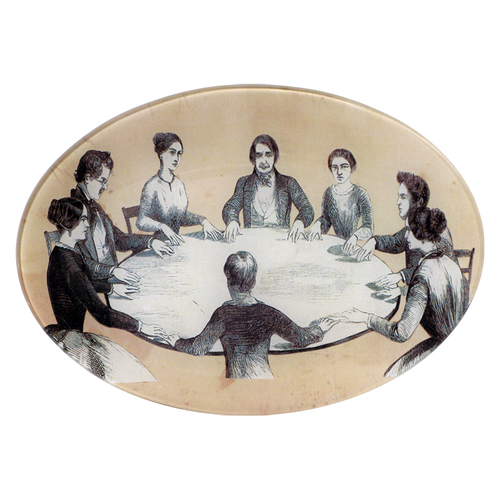 A seven inch by ten inch horizontal oval glass plate of black and white images of people sitting around a table, resembling a seance.