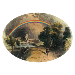 A seven inch by ten inch horizontal oval glass plate featuring a rainbow, with a person walking under the rainbow, surrounded by greenery and a building in the background.