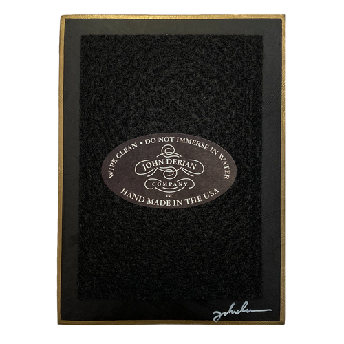 The back of a three and a half inch by five inch tray painted black with black felt and a painted gold boarder. Featuring the John Derian Company logo and sign signed by John Derian. 